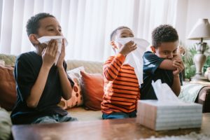 three-sick-children-coughing-and-sneezing-into-tissues